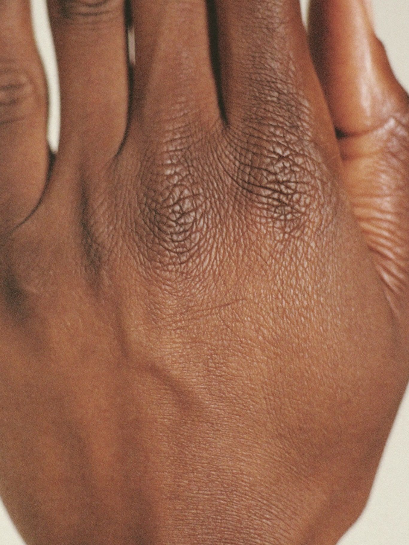 Two brown hands resting palm to palm, warm soft light