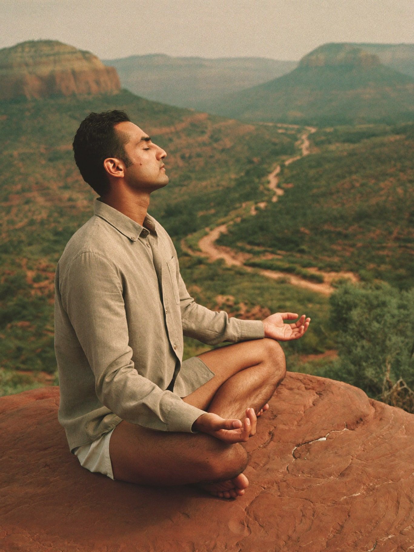 A man meditating on a sandstone ledge above the valley