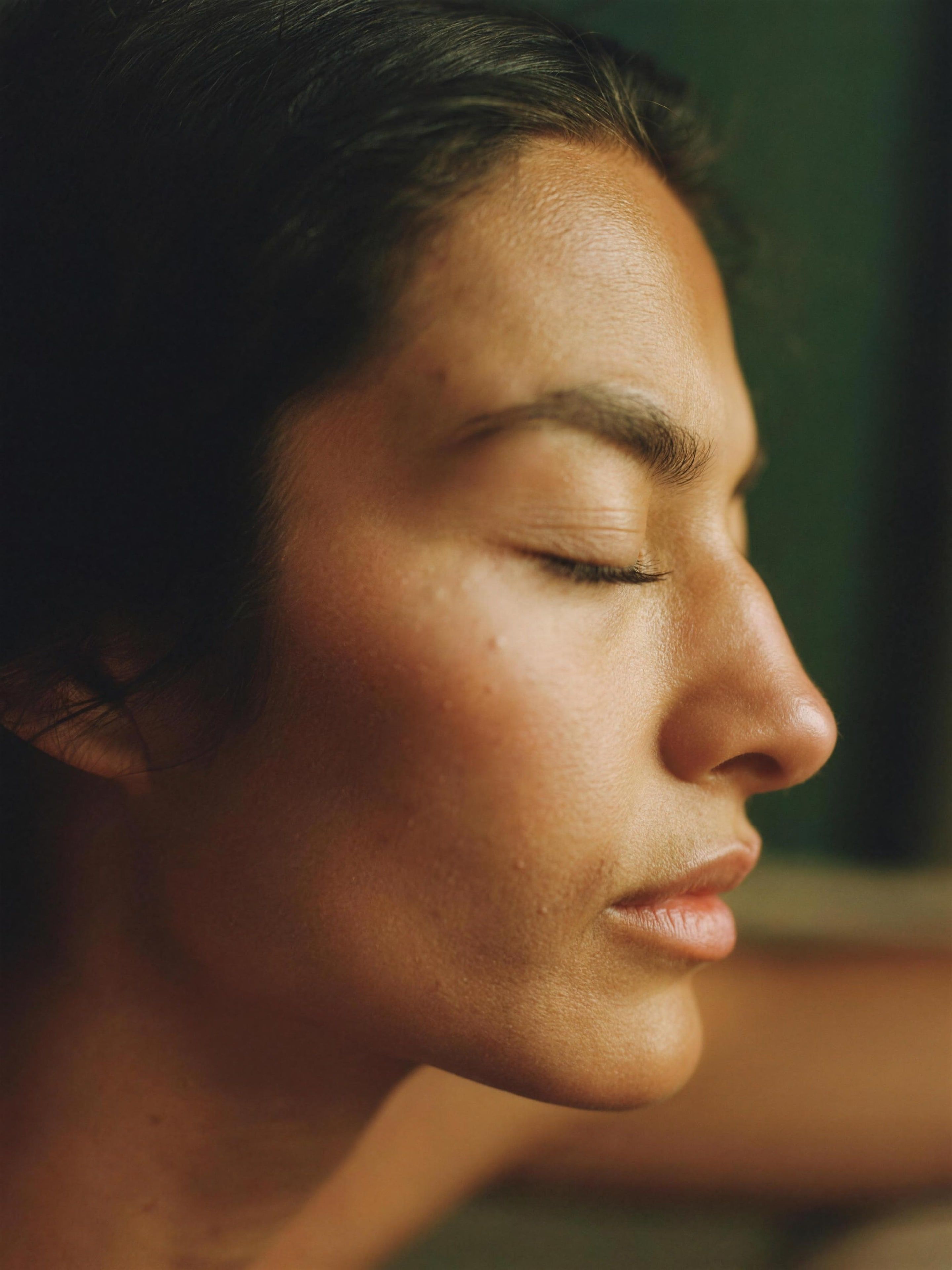 A woman with eyes closed in warm light