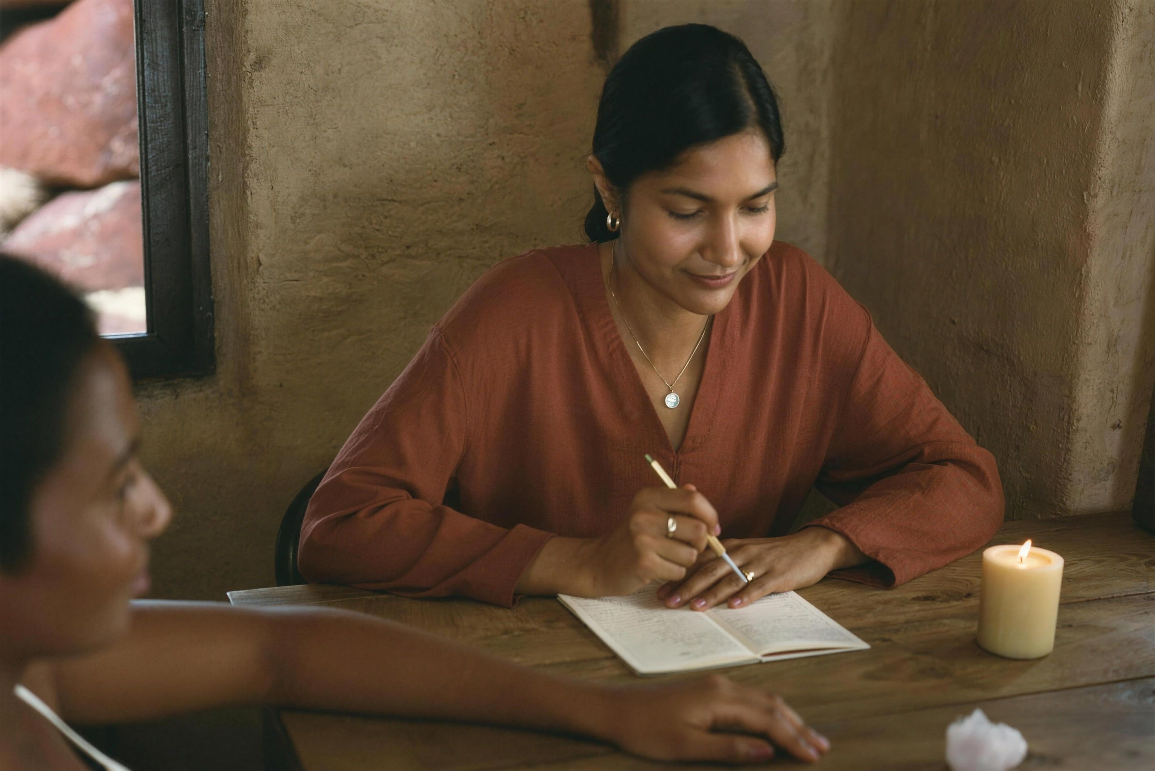 An intuitive energy reader taking notes during a reading at a wooden table